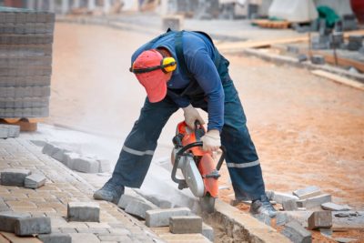 Man cutting through concrete while wearing PE equipment